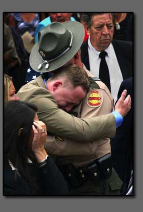 Officers embrace at funeral for slain trooper.